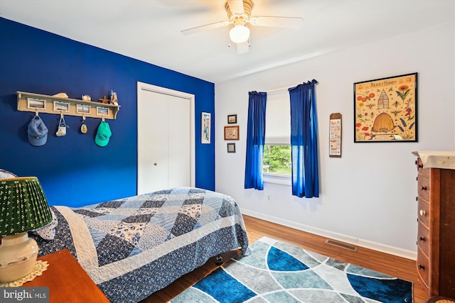 bedroom with wood finished floors, baseboards, a ceiling fan, and a closet