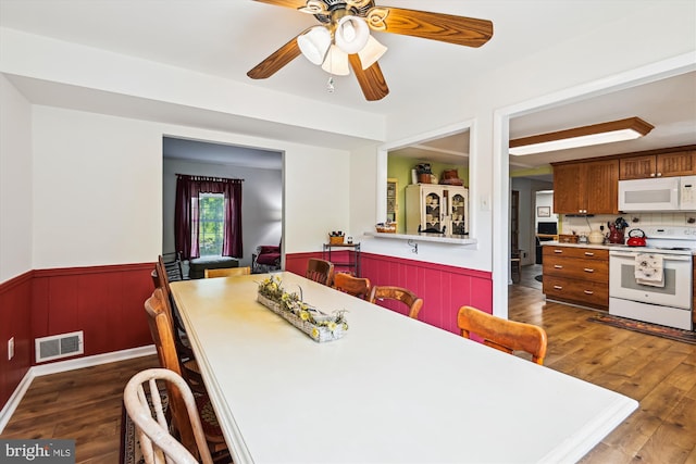 dining space with a wainscoted wall, wood finished floors, and a ceiling fan