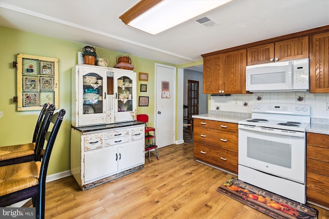 kitchen with white appliances, brown cabinetry, and light wood-style floors