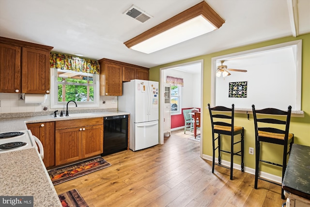 kitchen with white appliances, a sink, light countertops, ceiling fan, and light wood-style floors