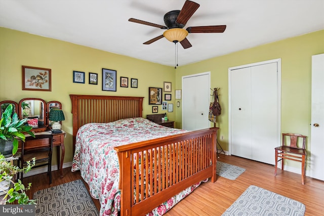 bedroom with wood finished floors, two closets, and a ceiling fan