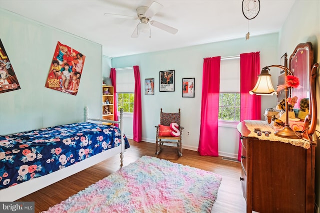 bedroom with multiple windows, wood finished floors, ceiling fan, and baseboards