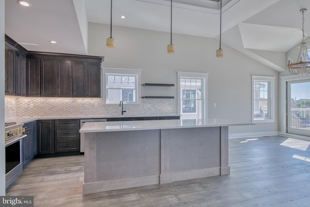 1306 N Barnegat Ave, Surf City, NJ 08008 - kitchen featuring appliances with stainless steel finishes, light countertops, dark brown cabinets, decorative backsplash, and a center island