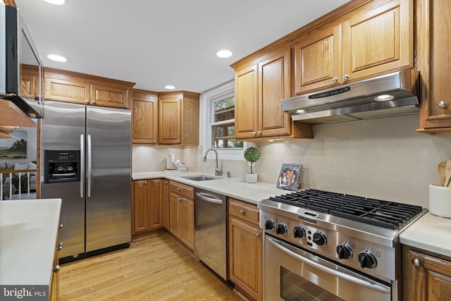14906 Cranoke St, Centreville, VA 20120 - kitchen featuring appliances with stainless steel finishes, a sink, under cabinet range hood, light wood-style flooring, and light countertops