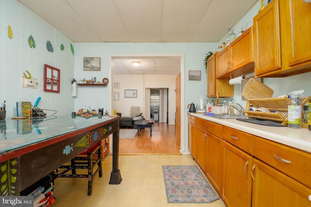 kitchen with light countertops, radiator, brown cabinets, a sink, and light floors
