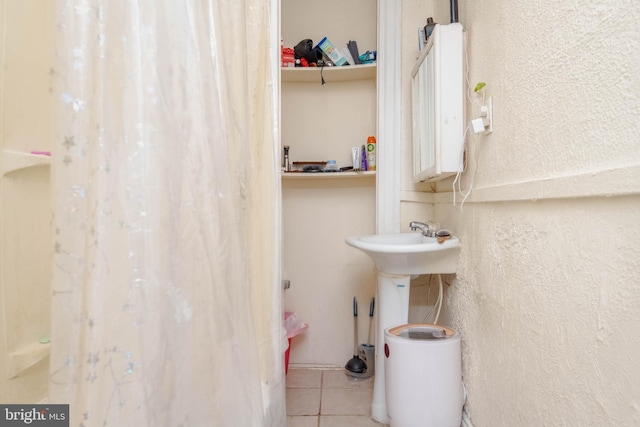 bathroom featuring tile patterned floors and a textured wall
