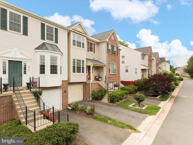 multi unit property featuring a residential view, a garage, driveway, and stairway