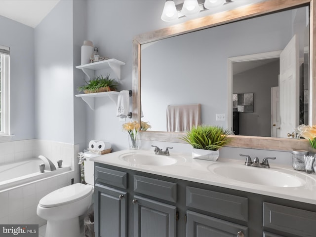 bathroom featuring double vanity, tiled tub, and toilet