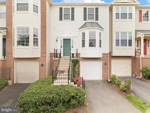 townhome / multi-family property featuring a garage, driveway, and brick siding