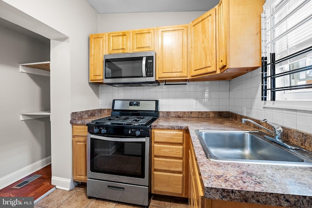 kitchen featuring stainless steel appliances, a sink, decorative backsplash, baseboards, and dark countertops