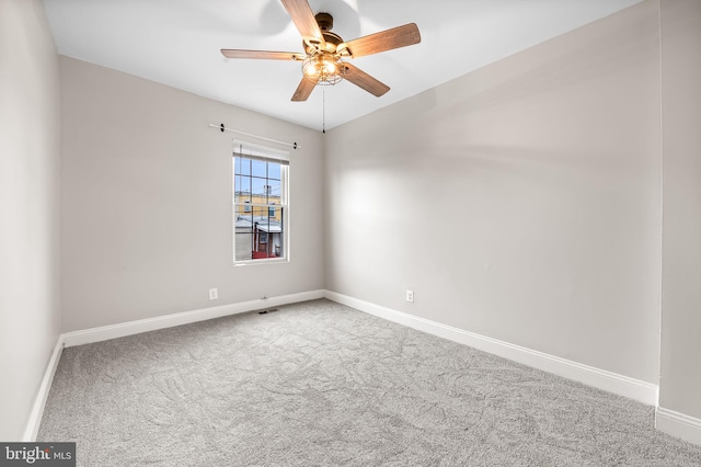 carpeted spare room featuring ceiling fan and baseboards