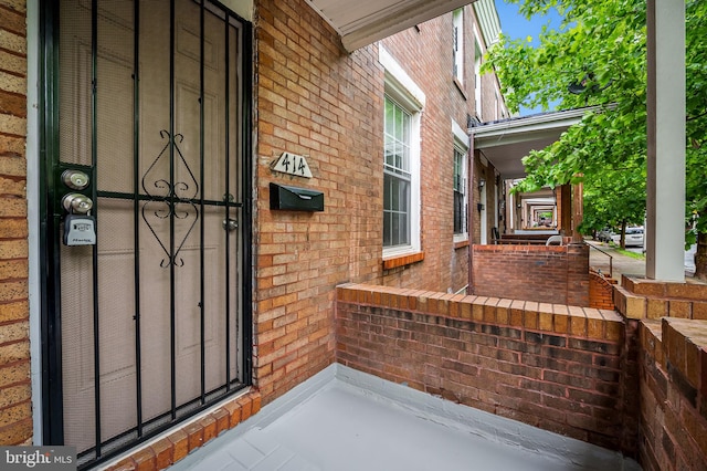 doorway to property with covered porch and brick siding