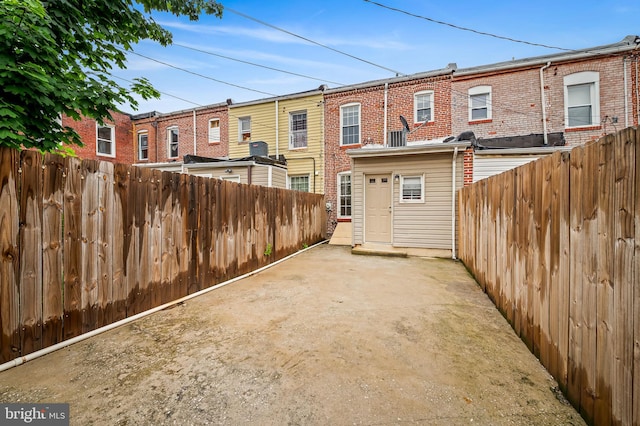 rear view of property featuring brick siding, a fenced backyard, and a patio