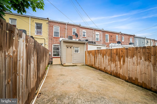 rear view of house with a fenced backyard, brick siding, a patio area, and cooling unit