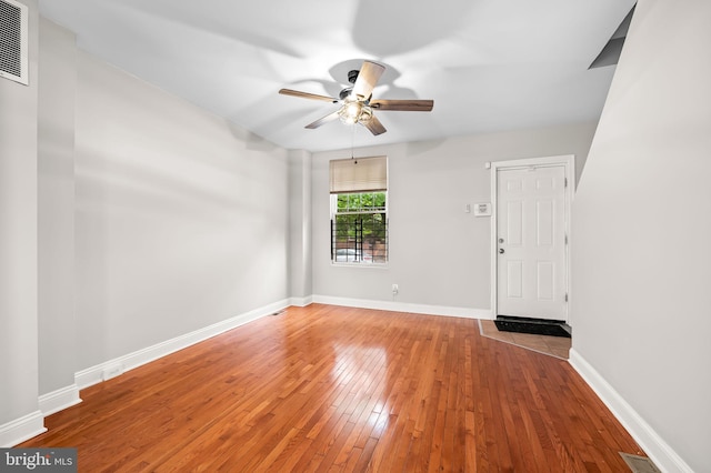 unfurnished room with a ceiling fan, hardwood / wood-style floors, and baseboards