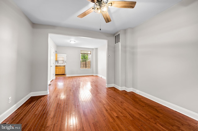 spare room featuring wood-type flooring, ceiling fan, and baseboards