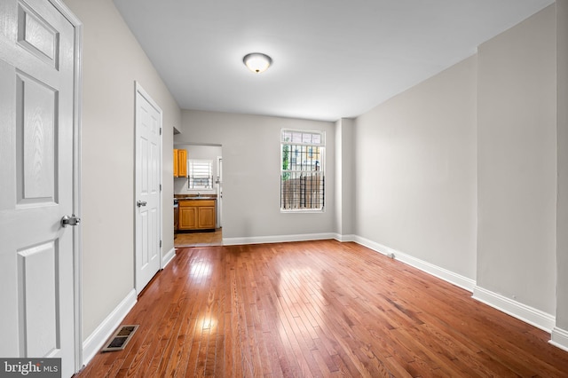 unfurnished living room featuring wood-type flooring and baseboards