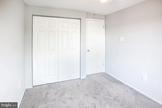 unfurnished bedroom featuring carpet, a closet, and baseboards