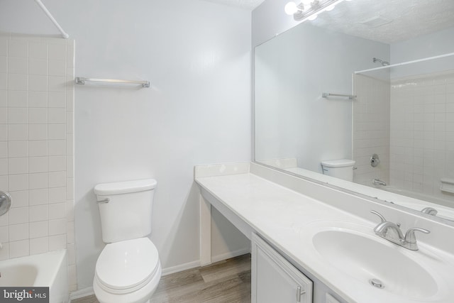 full bathroom with toilet, shower / bathtub combination, wood finished floors, vanity, and a textured ceiling