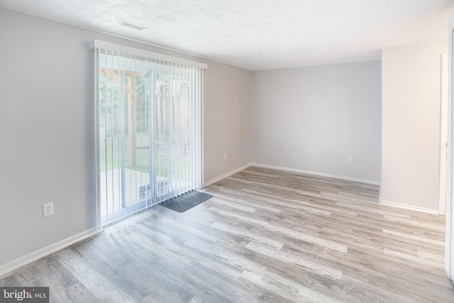 unfurnished room with wood finished floors, a textured ceiling, and baseboards