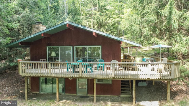 rear view of property with a chimney, a deck, and outdoor dining space