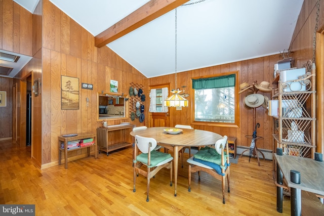 dining space featuring light wood-type flooring, wood walls, and baseboard heating