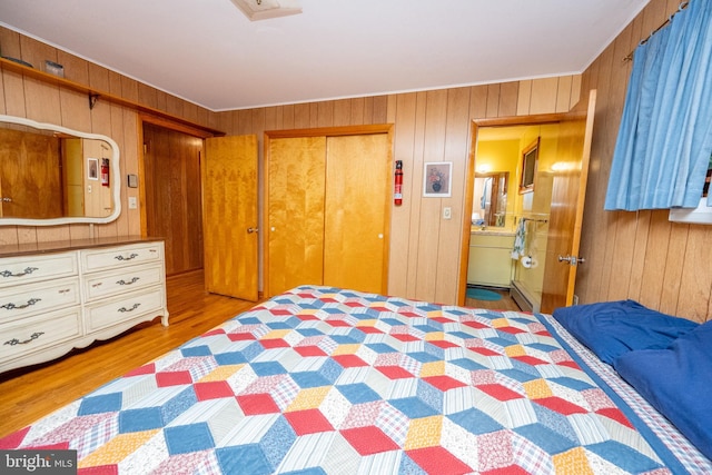 bedroom featuring wood walls, a closet, wood finished floors, ornamental molding, and a baseboard heating unit