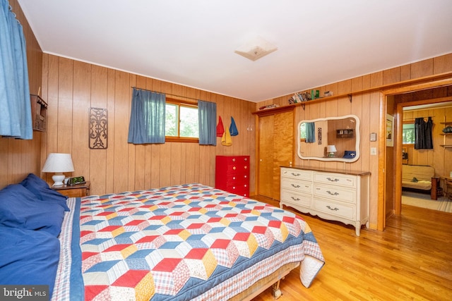 bedroom with wood walls, light wood-style floors, and a closet