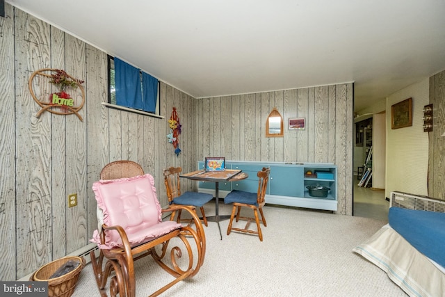 sitting room with carpet and wood walls