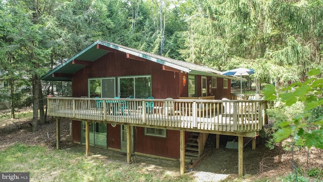 back of house with a deck and a wooded view