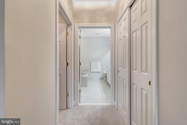 hall featuring carpet flooring, ornamental molding, and baseboards