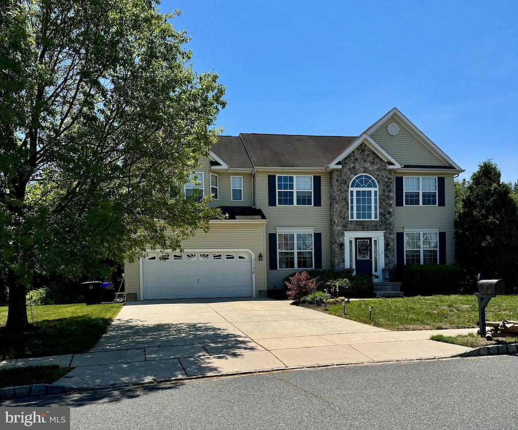 view of front facade with driveway, a front yard, and stone siding