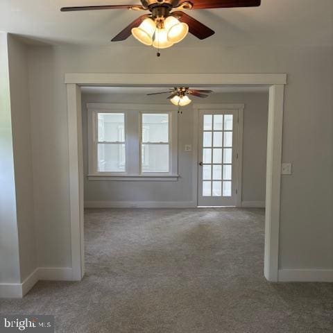 carpeted empty room with baseboards and a ceiling fan