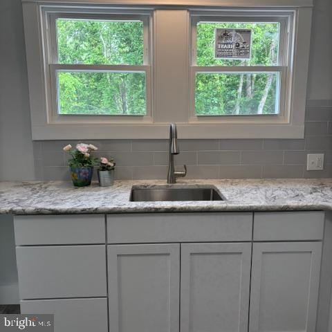 kitchen with a sink, decorative backsplash, white cabinetry, and plenty of natural light