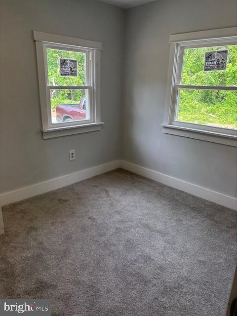 unfurnished room featuring carpet and baseboards