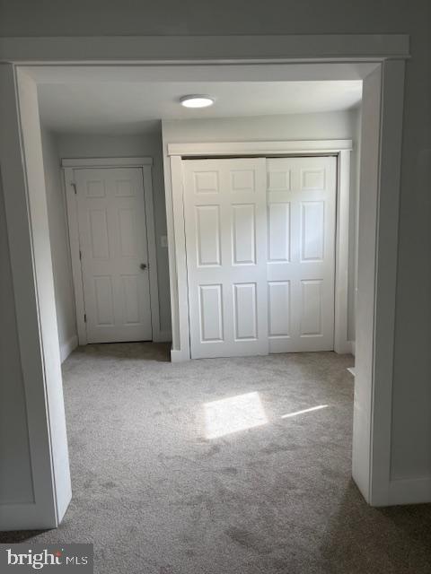 unfurnished bedroom with carpet, a closet, and baseboards
