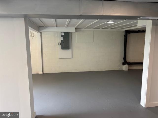 finished basement featuring electric panel and concrete block wall