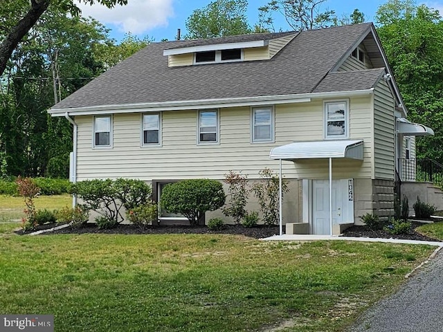 view of front of property with a front lawn and a shingled roof