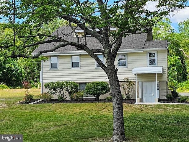 back of house with a lawn, a shingled roof, and a chimney