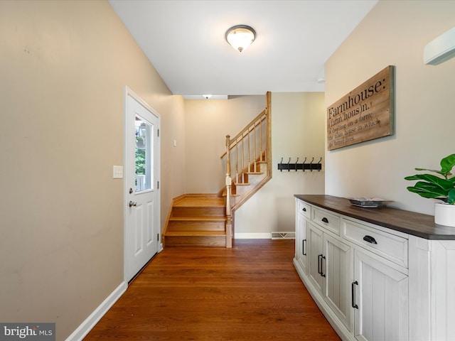 foyer entrance with stairs, baseboards, and dark wood-type flooring