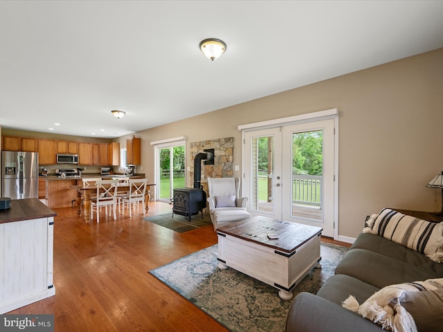 living room featuring a wood stove, wood finished floors, french doors, and recessed lighting