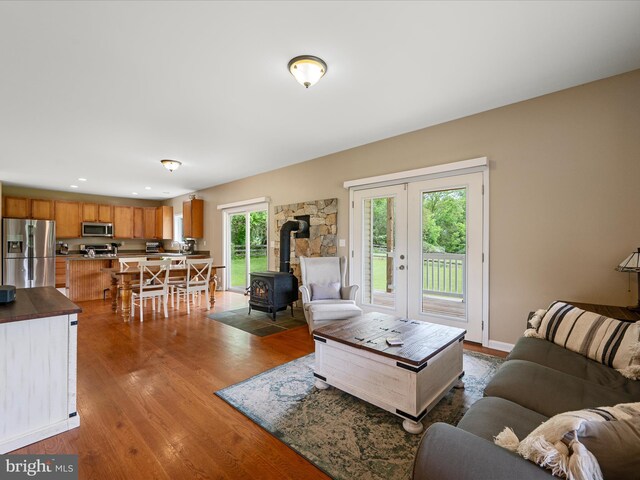 living area with a wood stove, wood finished floors, french doors, and recessed lighting