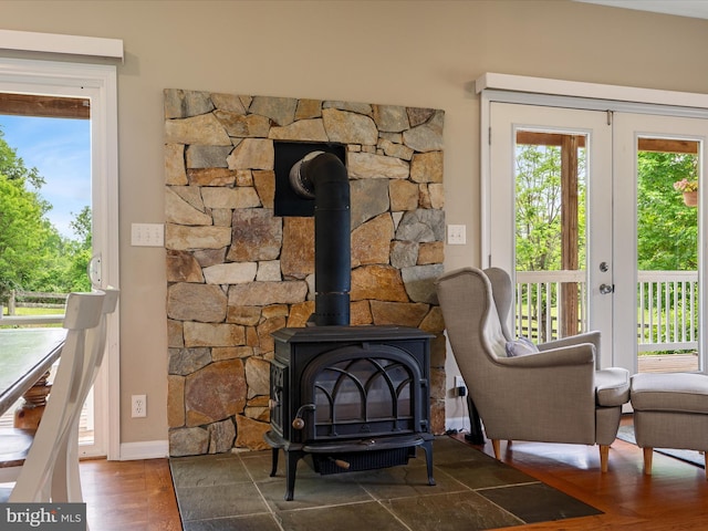 detailed view of a wood stove, wood finished floors, french doors, and baseboards