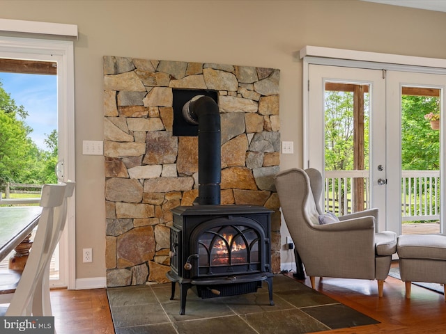 detailed view of a wood stove, wood finished floors, baseboards, and french doors
