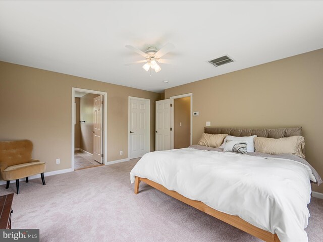 bedroom featuring light carpet, baseboards, ceiling fan, and connected bathroom