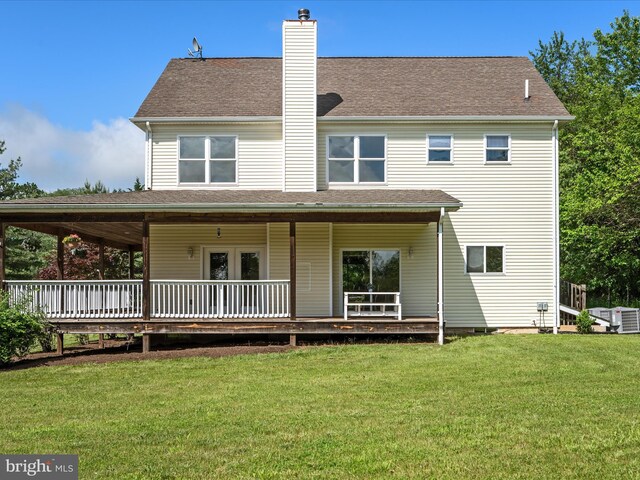 back of house with a chimney and a lawn