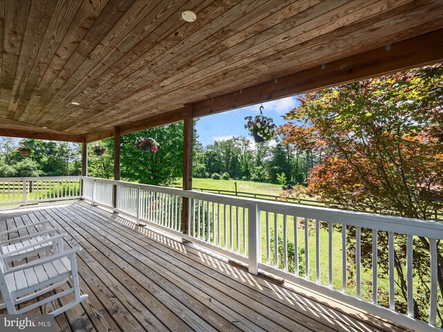 wooden deck with view of wooded area and a yard