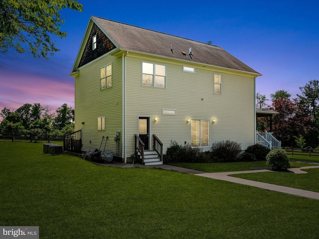 back of property at dusk featuring entry steps, a yard, and cooling unit