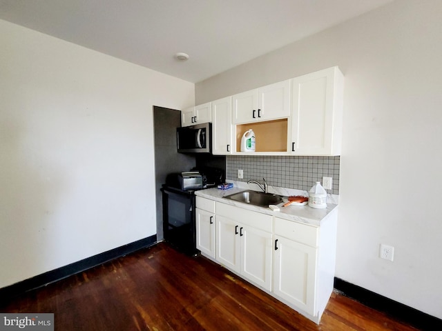 kitchen with stainless steel microwave, dark wood-type flooring, tasteful backsplash, black electric range, and a sink