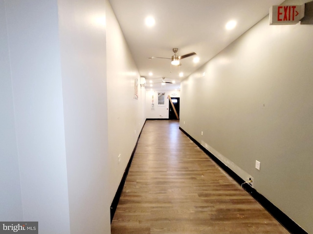 corridor featuring wood finished floors, recessed lighting, and baseboards